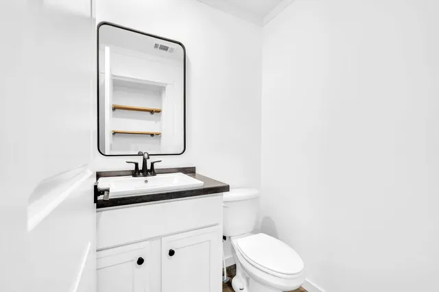a bathroom with a toilet sink vanity and mirror