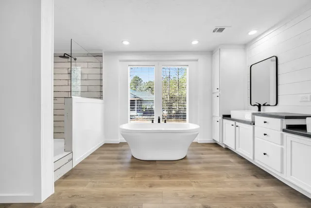 a spacious bathroom with a double vanity sink a large mirror and a bathtub