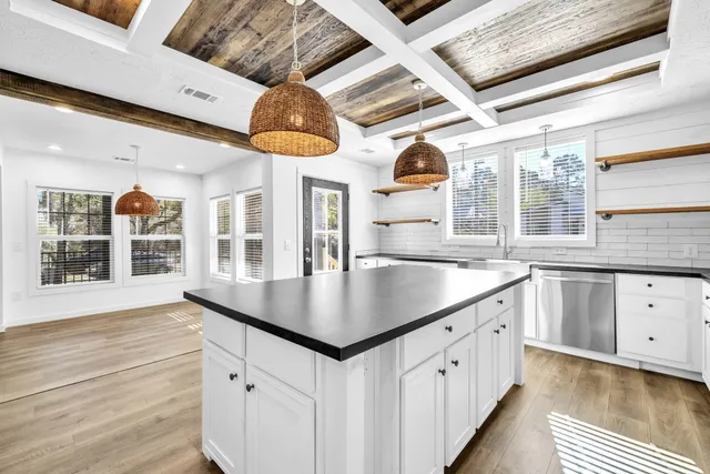 a kitchen with stainless steel appliances granite countertop a sink dishwasher and a large window with wooden floor