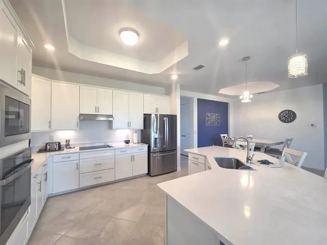 a large kitchen with stainless steel appliances lots of white cabinets