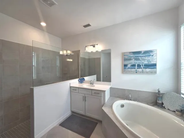 a bathroom with a tub a sink shower and mirror