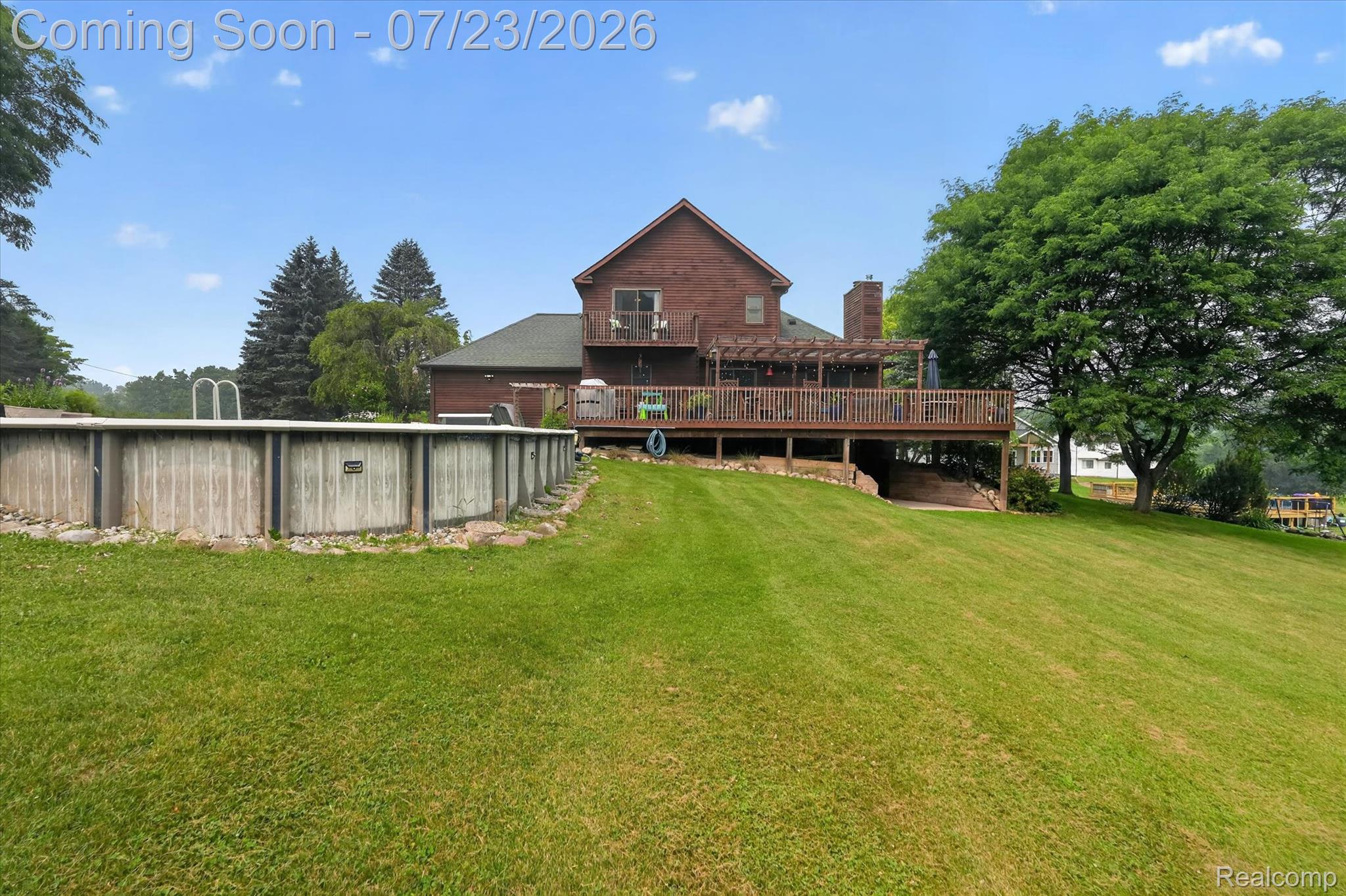 2795 Bird Road Ortonville, MI 48462 - Photo 49 of 62 Expansive backyard featuring a large lawn, an above-ground swimming pool, and a multi-level wood deck