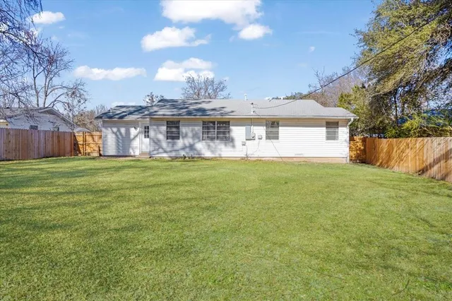 a view of a house with a yard and a large tree