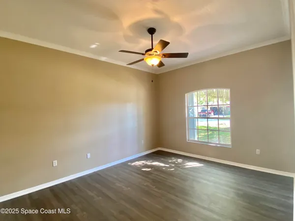 a view of an empty room with window and wooden floor