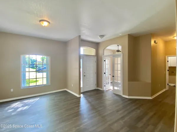 a view of an empty room with wooden floor and a window