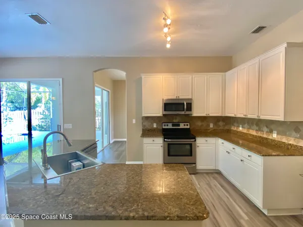 a kitchen with stainless steel appliances granite countertop a stove top oven a sink and a refrigerator