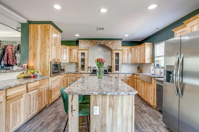 a kitchen with stainless steel appliances granite countertop a kitchen island hardwood floor sink stove and granite counter top