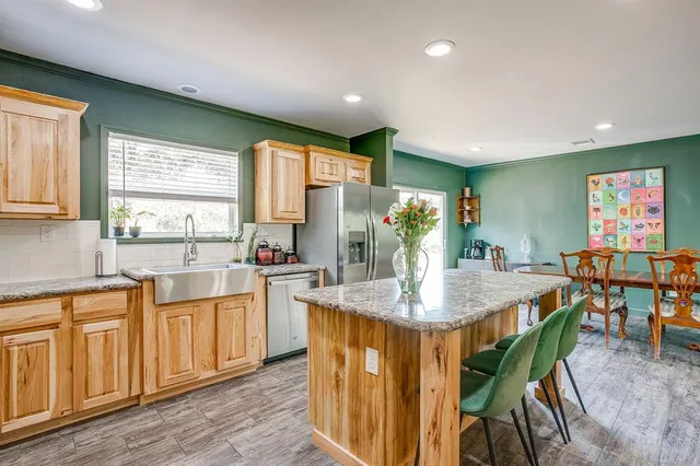 a kitchen with stainless steel appliances granite countertop a table chairs sink and window