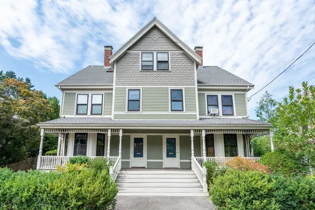 a front view of a house with a yard and potted plants