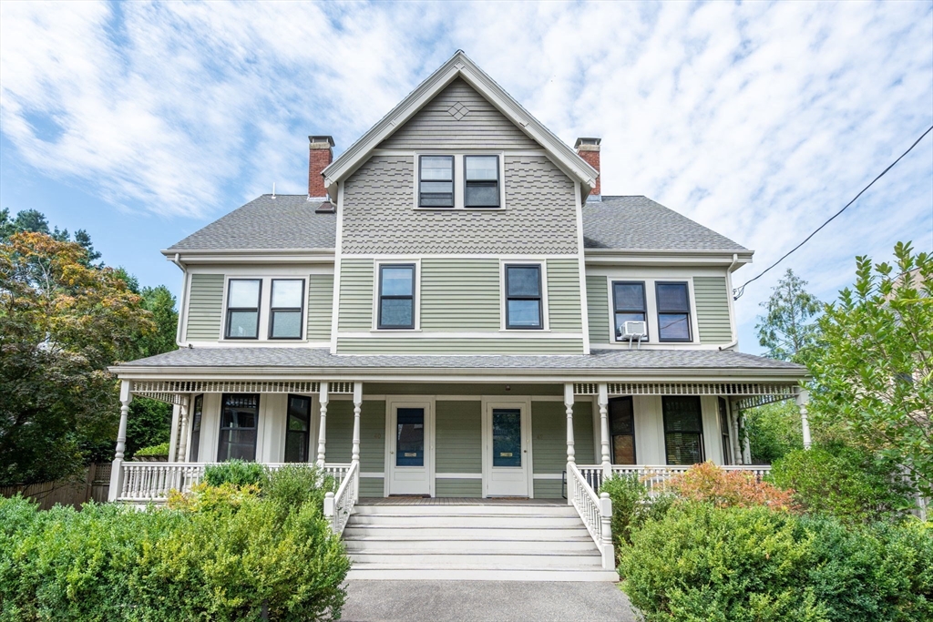 a front view of a house with a yard and potted plants