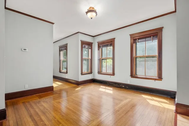 a view of an empty room with a window and wooden floor
