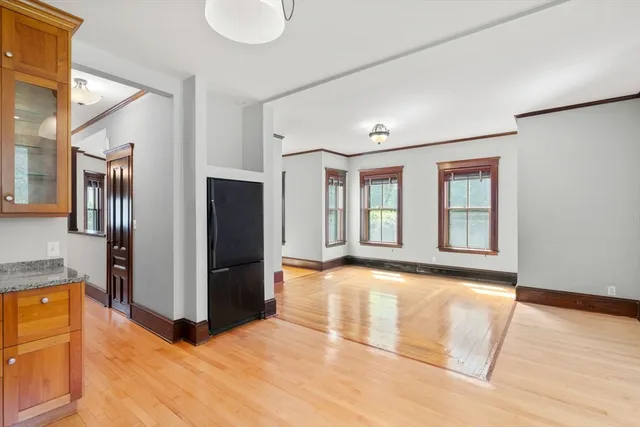 a view of an empty room with window and wooden floor