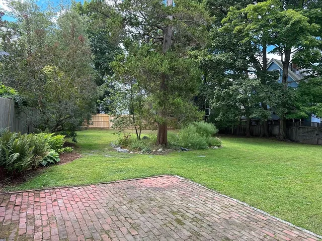 a backyard of a house with lots of green space and wooden fence
