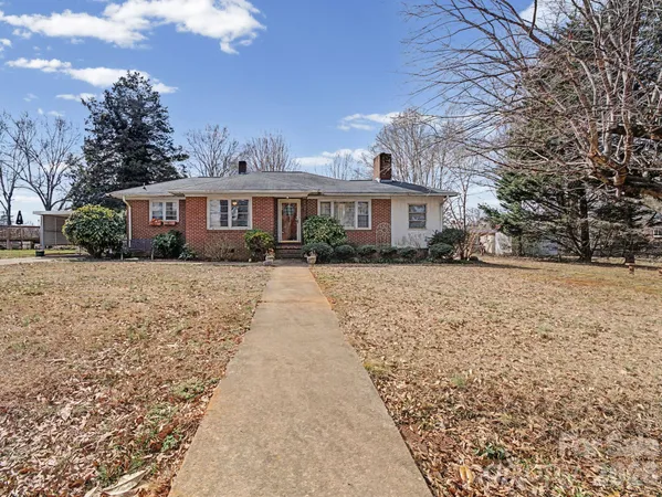 a front view of a house with a yard covered with trees