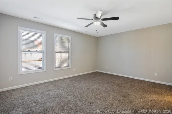 an empty room with windows and fan
