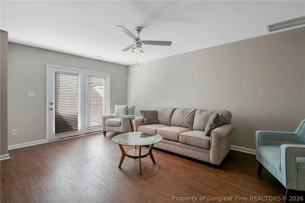 a view of an empty room and kitchen with wooden floor