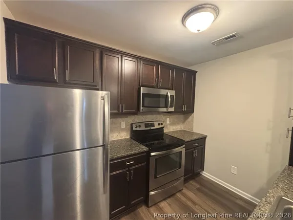 a kitchen with stainless steel appliances granite countertop a refrigerator a stove a sink and a microwave