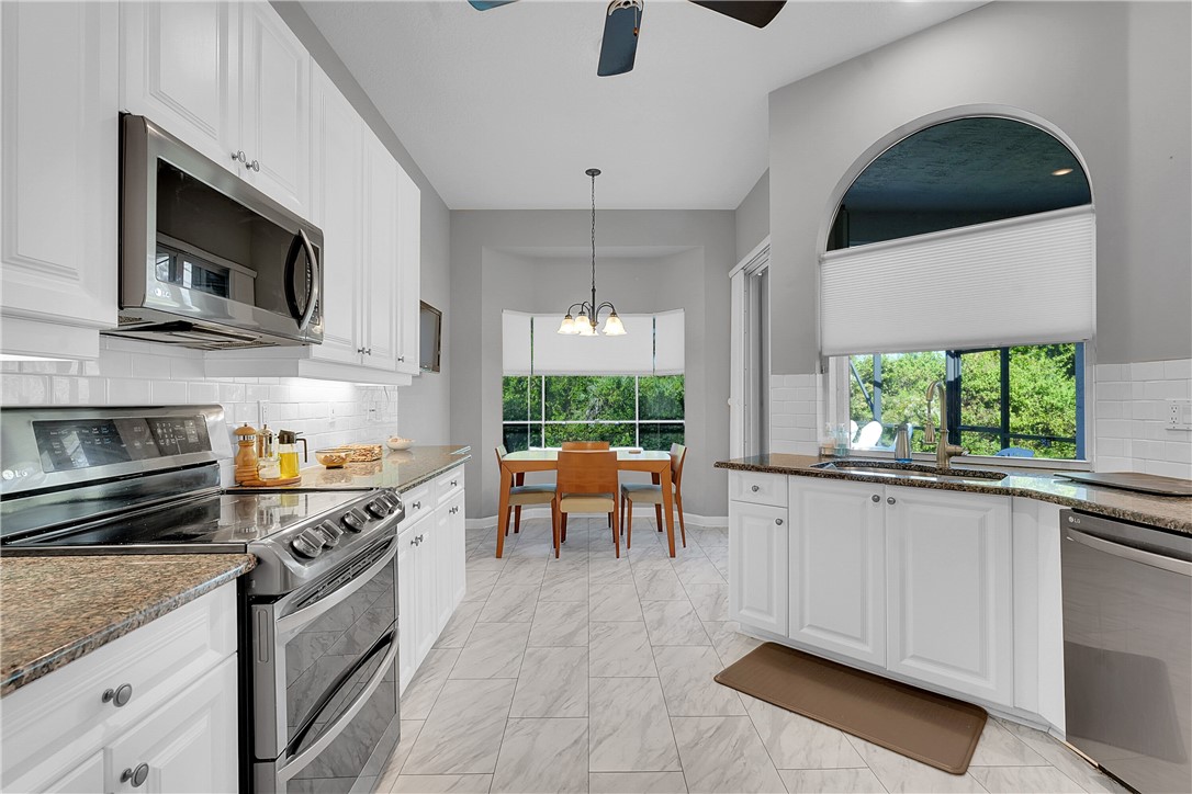 715 Southwest Munjack Circle Port St. Lucie, FL 34986 - Photo 4 of 36 a kitchen with stainless steel appliances kitchen island granite countertop a stove a sink and a microwave