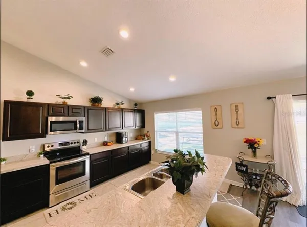 a kitchen with stainless steel appliances kitchen island granite countertop a refrigerator and a sink