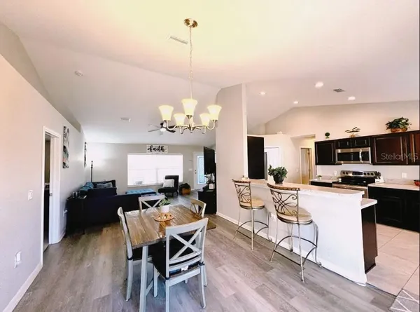 a view of a dining room and livingroom with furniture wooden floor a chandelier