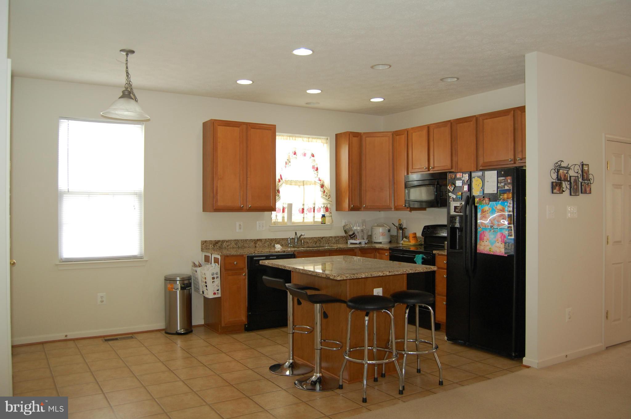 9604 Maxwell Road Middle River, MD 21220 - Photo 7 of 16 a kitchen with stainless steel appliances granite countertop a stove a refrigerator a sink a dining table and chairs