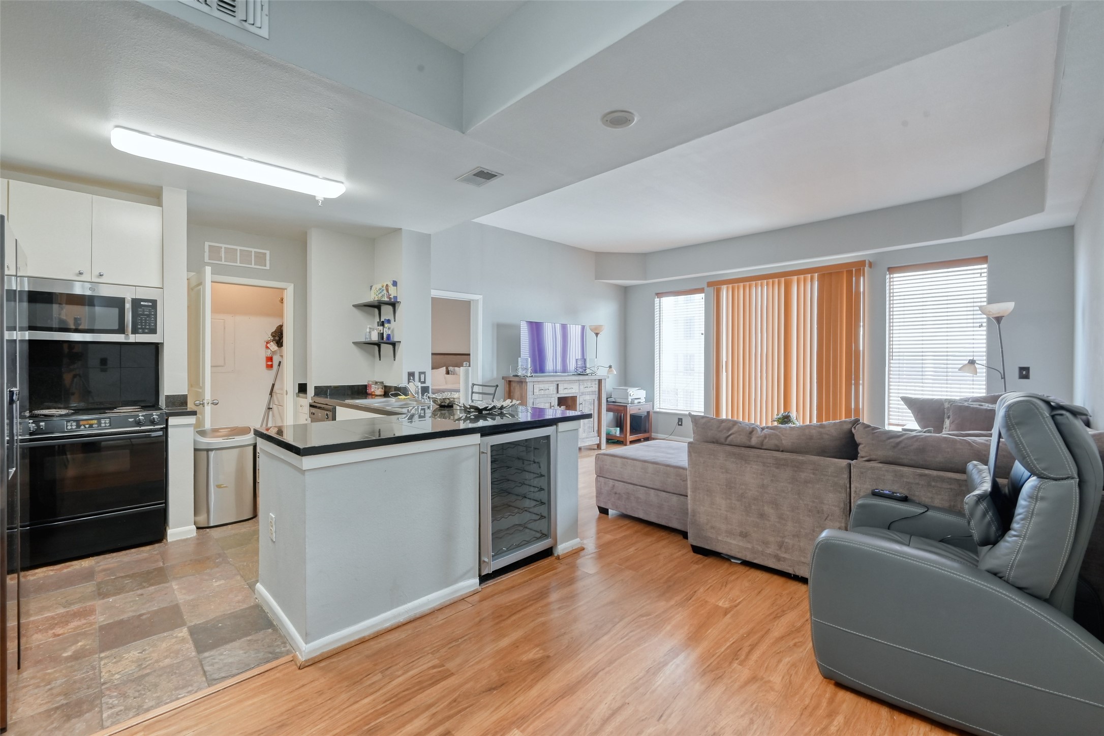 3505 Sage Road, Unit 1206 Houston, TX 77056 - Photo 27 of 50 a large living room with stainless steel appliances granite countertop a stove a sink dishwasher a refrigerator and a dining table with wooden floor