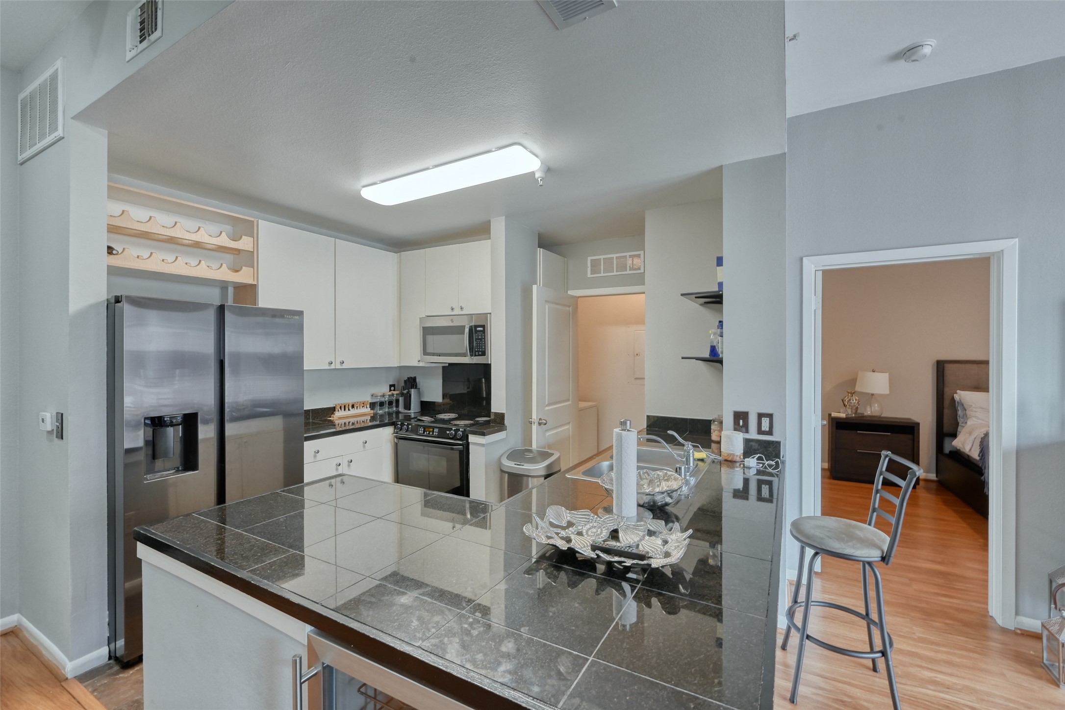 3505 Sage Road, Unit 1206 Houston, TX 77056 - Photo 28 of 50 a kitchen with stainless steel appliances kitchen island granite countertop a refrigerator a stove a sink and white cabinets