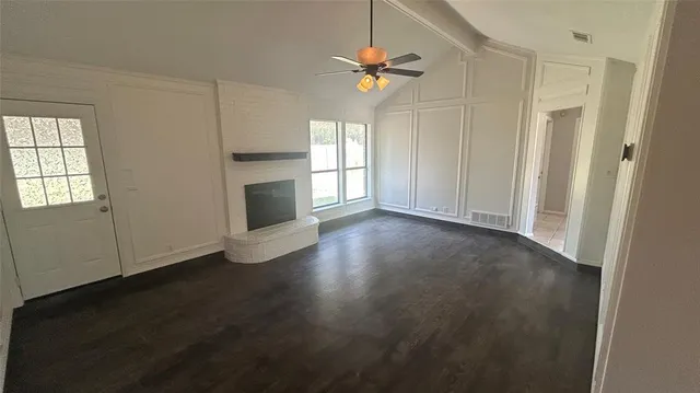 an empty room with windows fireplace and sink