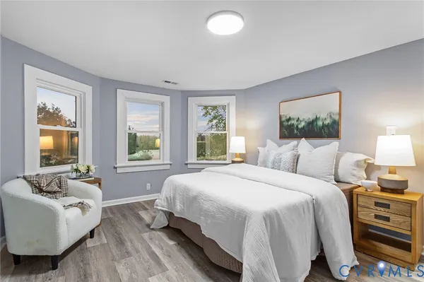 a spacious bedroom with a bed and wooden floor