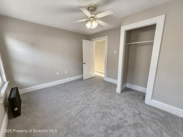 an empty room with closet and a chandelier fan