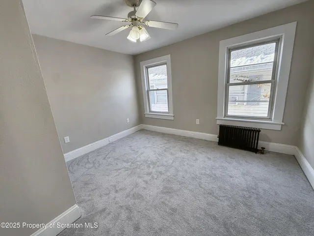 an empty room with windows and fan