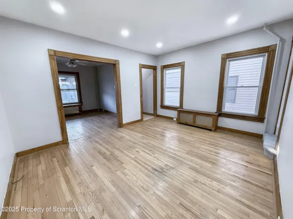 an empty room with wooden floor and windows