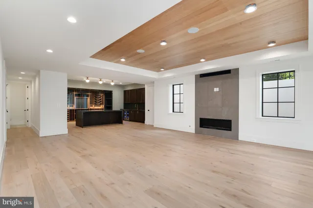 a view of an empty room with kitchen and window