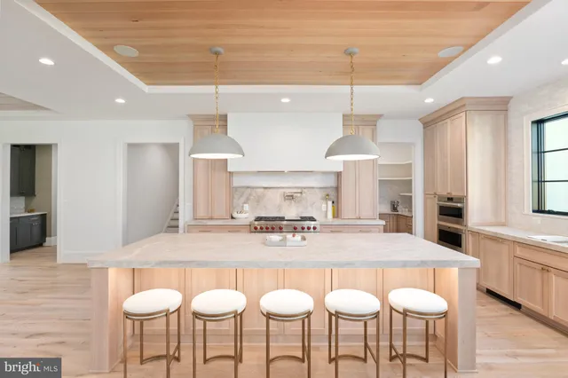 a kitchen with stainless steel appliances granite countertop a dining table chairs and white cabinets
