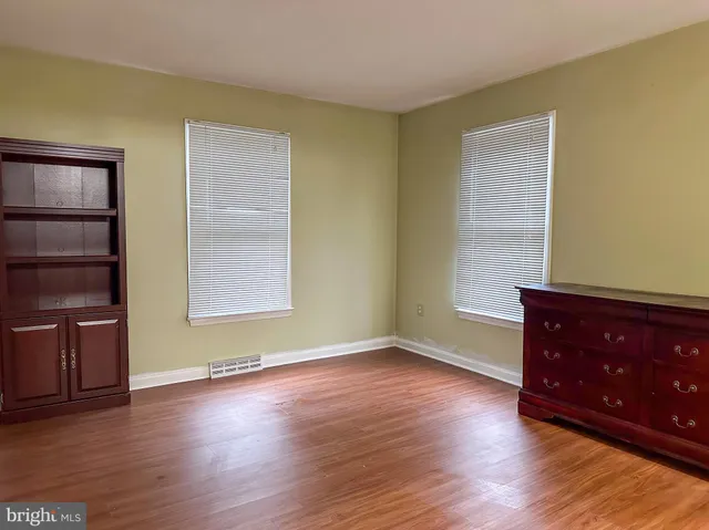 an empty room with wooden floor closet and windows