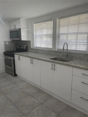 a kitchen with granite countertop white cabinets and a sink