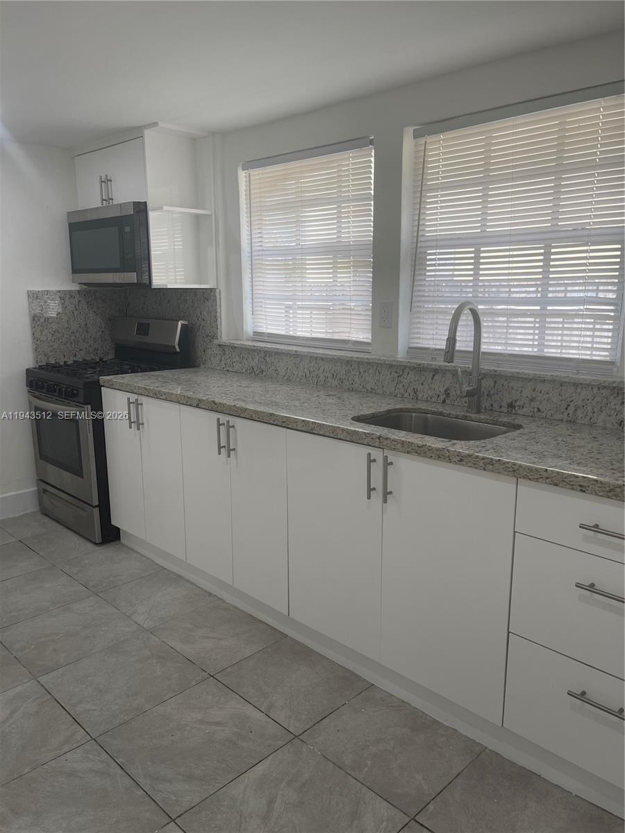 317 East 8th Street, Unit 1 Hialeah, FL 33010 - Photo 5 of 21 a kitchen with granite countertop white cabinets and a sink