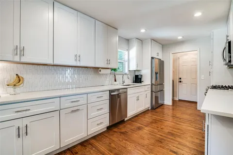 a kitchen with white cabinets and refrigerator