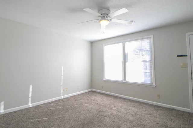an empty room with a window and a fan