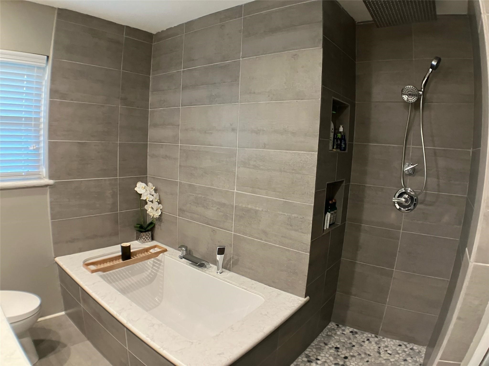 3027 Guese Road Houston, TX 77018 - Photo 16 of 22 Renovated bathroom includes stylish tile work and a refreshed tub area with modern appeal.