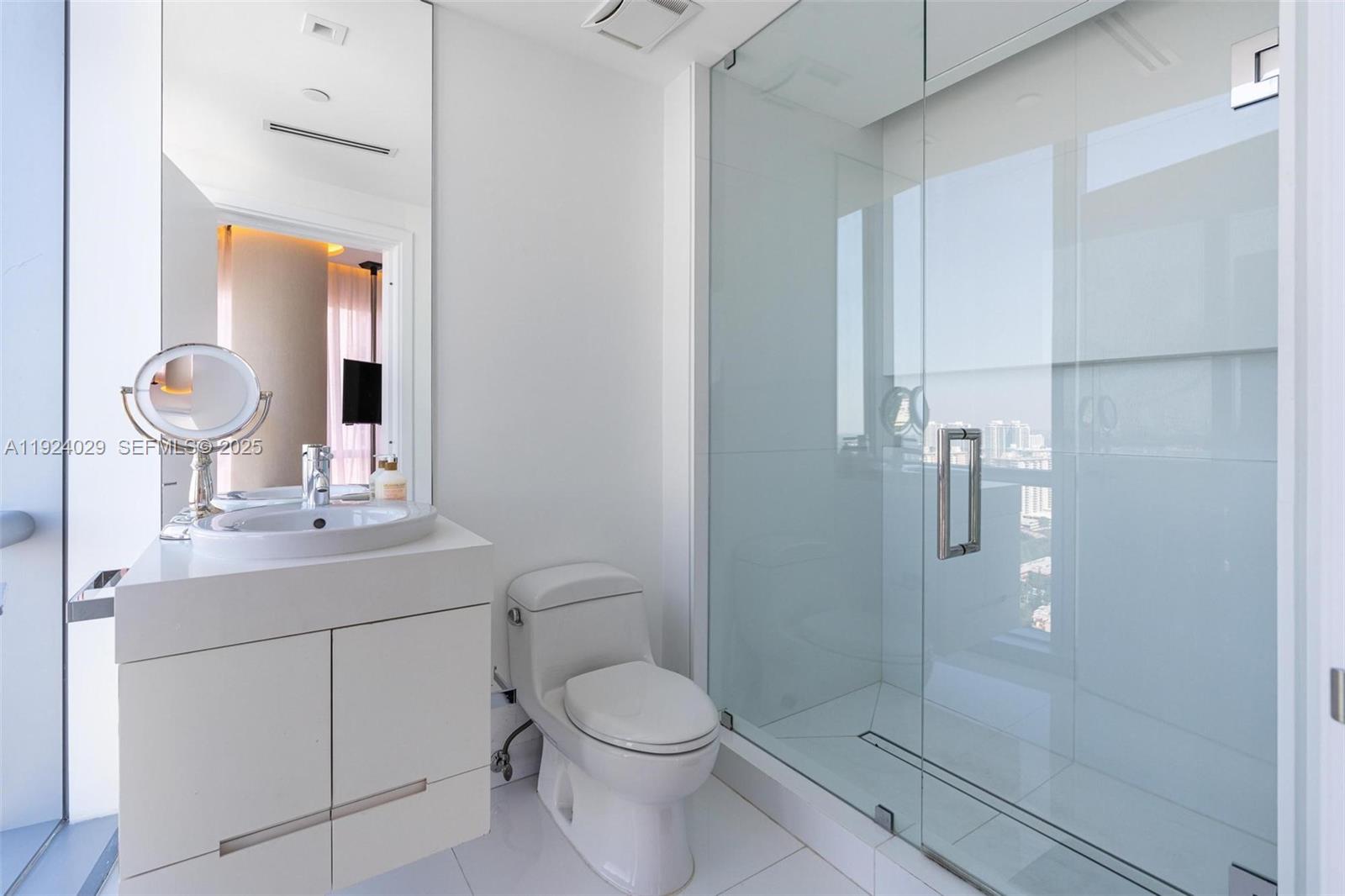 17121 Collins Avenue, Unit 3201 Sunny Isles Beach, FL 33160 - Photo 22 of 36 a bathroom with a toilet a sink a mirror and shower