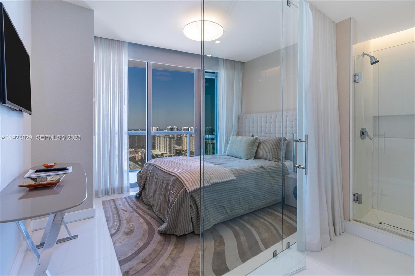 17121 Collins Avenue, Unit 3201 Sunny Isles Beach, FL 33160 - Photo 25 of 36 a bedroom with a bed and a chandelier