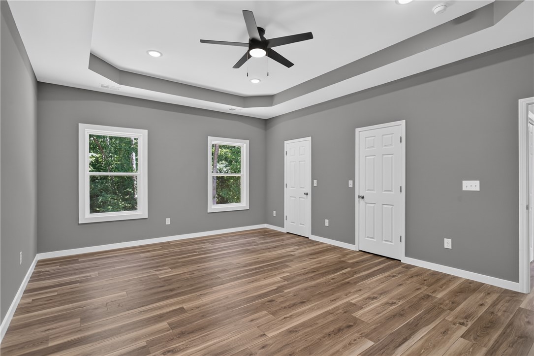 223 Maple Drive Anderson, SC 29621 - Photo 20 of 45 A spacious primary bedroom features rich wood flooring, a tray ceiling, and multiple sun-filled windows.