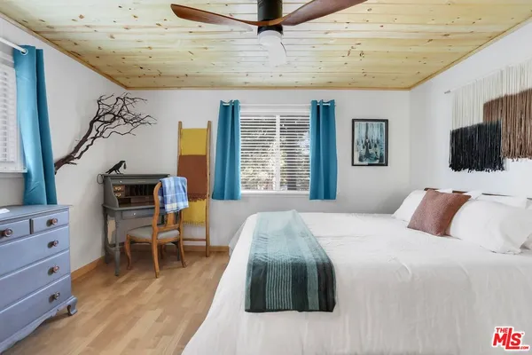 a bedroom with a large bed and a flat tv screen on dresser