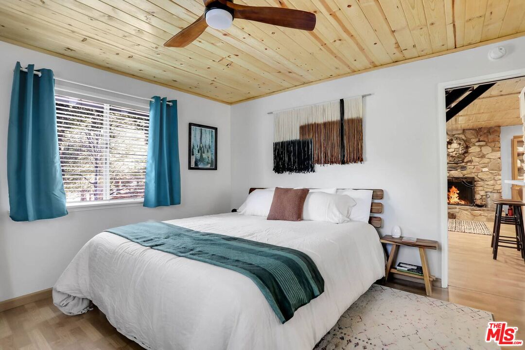 52521 Pine Ridge Road Idyllwild, CA 92549 - Photo 27 of 43 a spacious bedroom with a bed a flat screen tv and a large window