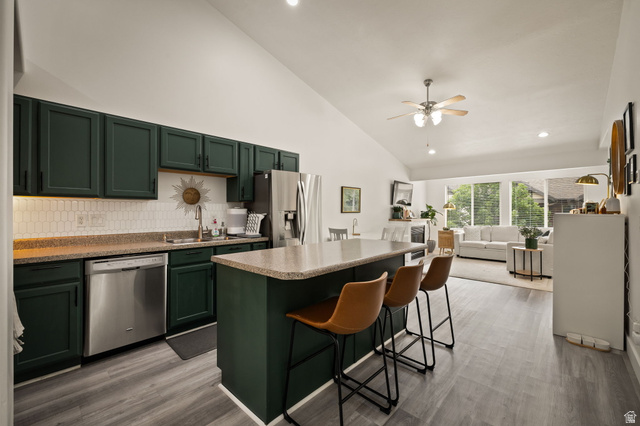 204 Lyman Lane Bountiful, UT 84010 - Photo 5 of 28 Open-concept kitchen featuring dark green cabinetry, stainless steel appliances, and a central island with bar seating