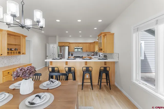 a dining room with kitchen island stainless steel appliances furniture large window and wooden floor