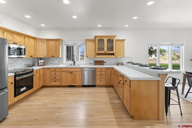 a kitchen with stainless steel appliances granite countertop wooden cabinets a sink a stove a refrigerator and island