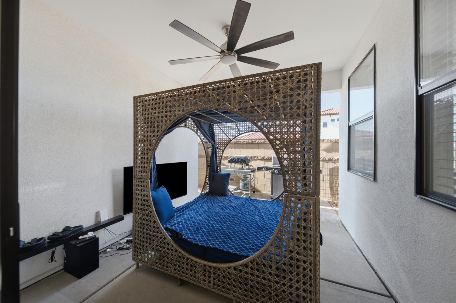 6144 Red Sand Lane St. George, UT 84790 - Photo 19 of 19 One of the home's true showstoppers: a hand-woven rattan cabana daybed dressed in deep cobalt cushions, tucked into a flexible bonus space with its own ceiling fan and patio access. Equal parts reading nook and design statement, it's the kind of feature buyers remember long after the showing ends.