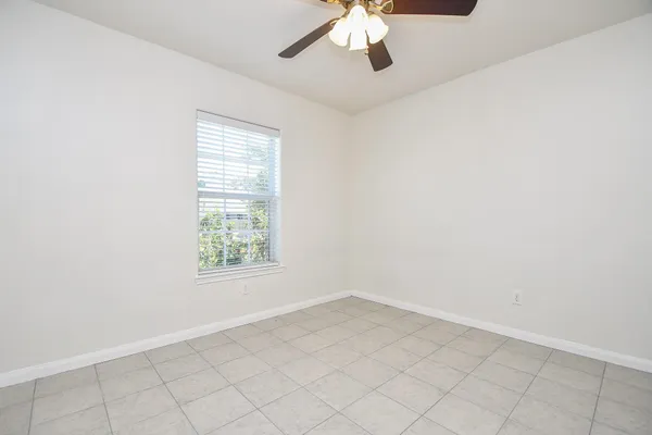 an empty room with a ceiling fan and window